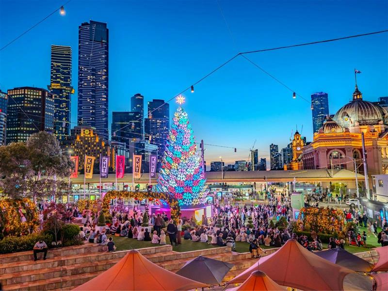 A large Christmas tree is illuminated, with Flinders Street Station in the background