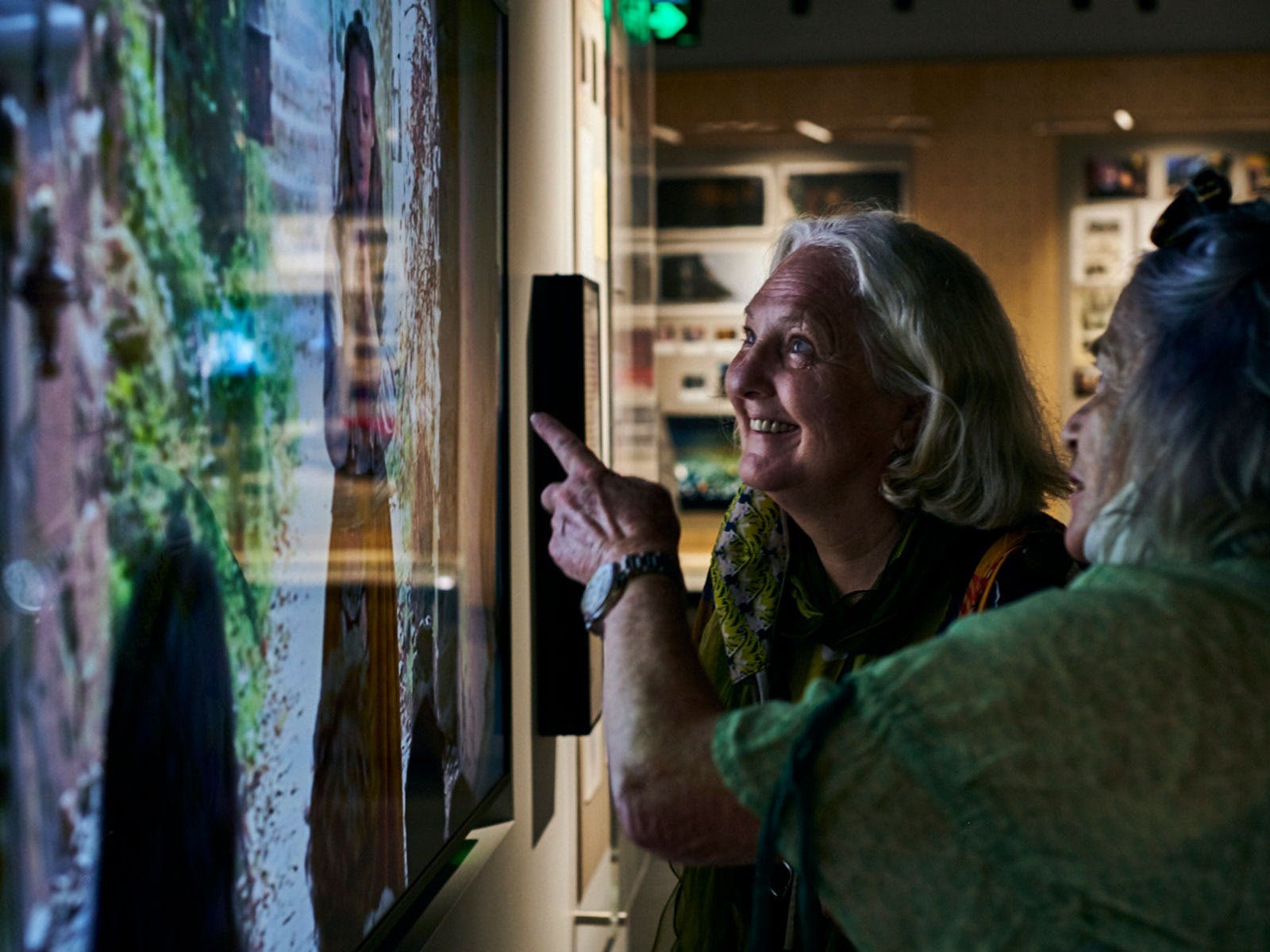 Two older women look and point at a screen