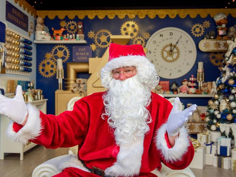 A man dressed as Santa in a red suit and hat with white beard