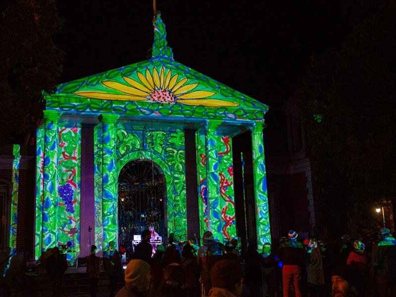 Image of historical building with a colourful projection and crowd gathering