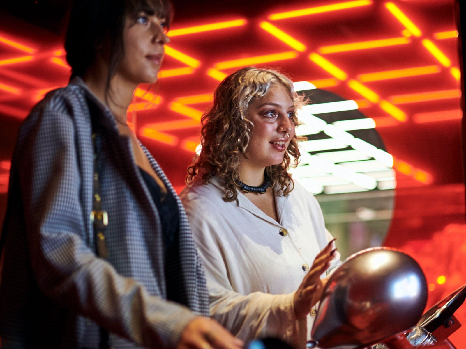 Two women touch silver objects in front of them