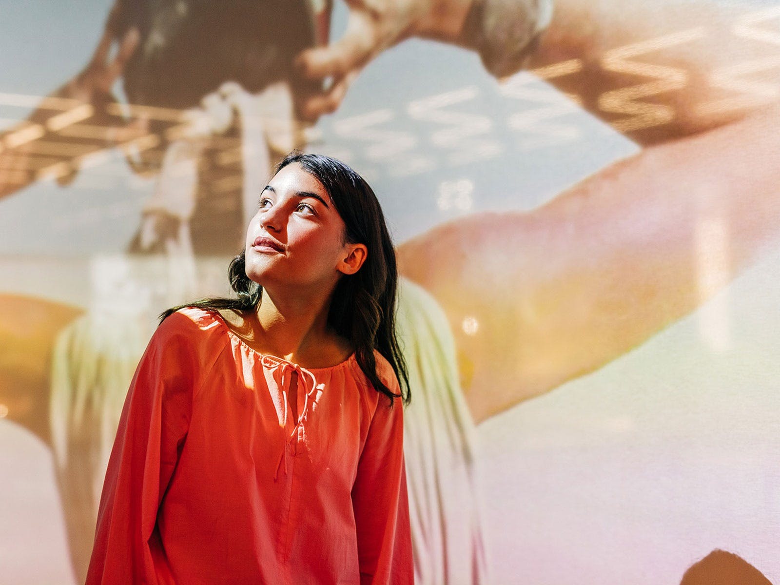 A young woman looks up, with projection behind her